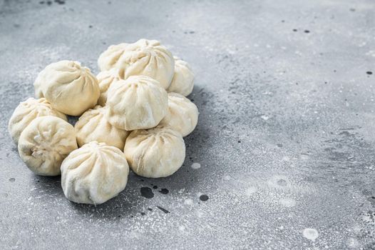 Frozen uncooked baozi dumplings stuffed with meat. Gray background. Top view. Copy space.