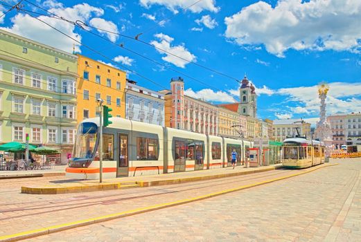 Linz - June 2020, Austria: View of the main square of Linz with colorful buildings, tram stop and modern trams