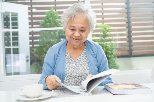 Asian senior or elderly old lady woman reading a book for practice brain while living at home, resting hobby retirement concept.