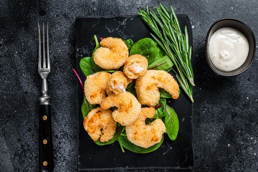 Roasted Crispy Shrimps Prawns on a marble board with green salad. Black background. Top view.