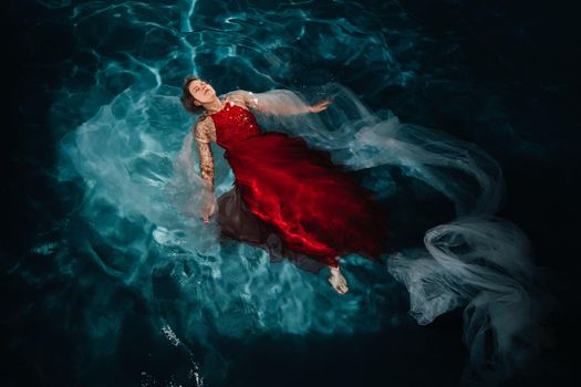 A girl in a red dress is floating on the water.A journey on the water of a single woman.