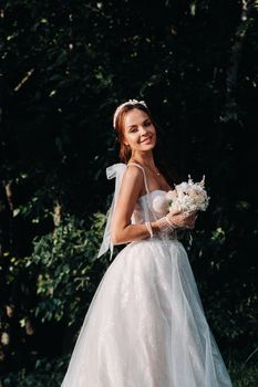 portrait of an elegant bride in a white dress with a bouquet in nature in a nature Park.Model in a wedding dress and gloves and with a bouquet .Belarus.