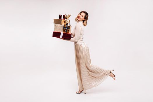 A girl in a skirt and jacket with a lot of gifts in her hands on a white background