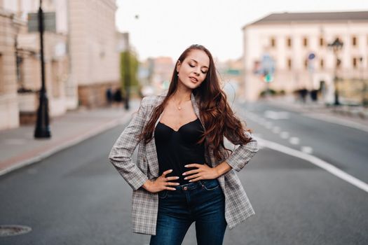 a girl in a jacket and long hair walks through the old city.A beautiful girl smiles.Girl on the road.