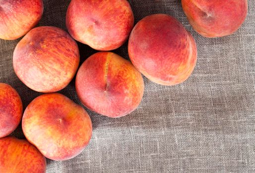 folded in a pile on a linen tablecloth ripe orange peaches of a large size,