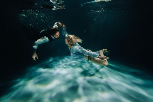A woman and a man meet under water.A couple of lovers under water.