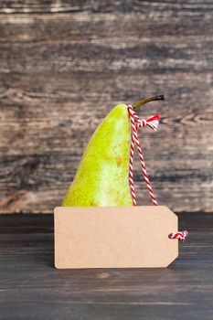 one green long old pear on a black stolus with a tag for price, discounts, advertisements or other messages, closeup