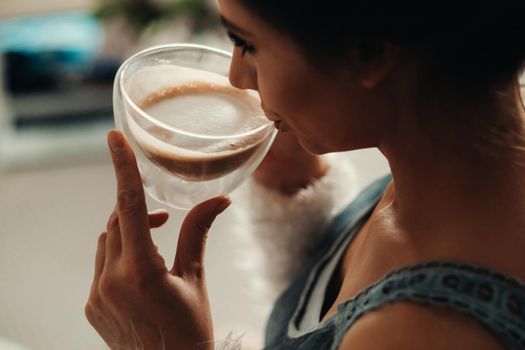 a relaxed girl at home drinks coffee and watches a movie.Domestic calm.The girl is sitting comfortably on the sofa and drinking coffee.