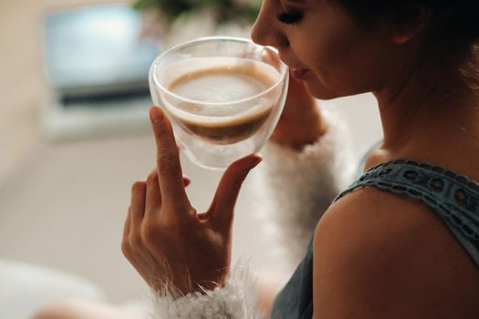 a relaxed girl at home drinks coffee and watches a movie.Domestic calm.The girl is sitting comfortably on the sofa and drinking coffee.