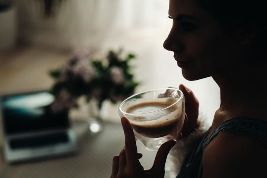 a relaxed girl at home drinks coffee and watches a movie.Domestic calm.The girl is sitting comfortably on the sofa and drinking coffee.