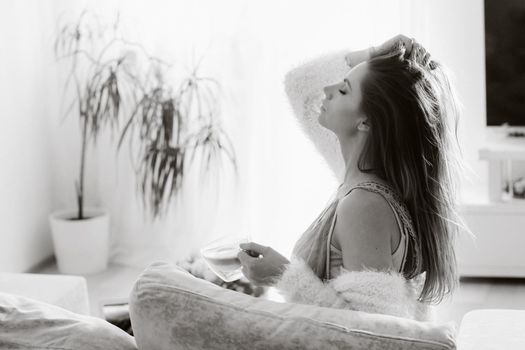 a relaxed girl at home drinks coffee and watches a movie.Domestic calm.The girl is sitting comfortably on the sofa and drinking coffee.black and white photo.