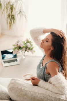 relaxed girl at home drinking coffee.Inner peace.The girl is sitting comfortably on the sofa and drinking coffee.