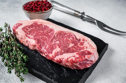 Raw striploin or new york strip steak on a marble board. White background. Top view.