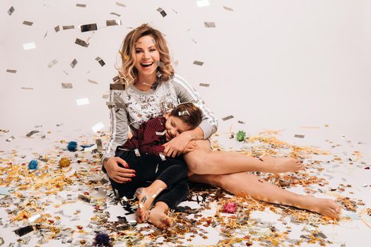 Portrait of a happy mother and son on a white background in confetti.