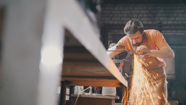 Grinding metal tools with sparkles - forge workshop, manufacturing