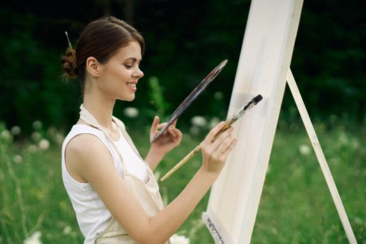 woman artist with palette of paints drawing easel nature hobby. High quality photo