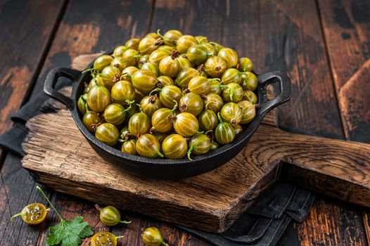 Ripe Green gooseberries ready for cooking jam. Dark Wooden background. Top view.