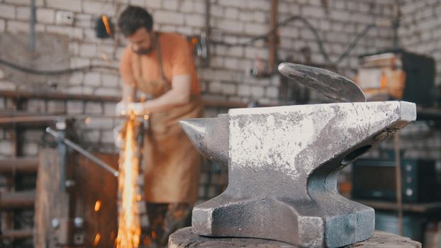 Blacksmith working a circular saw about anvil, a lot of sparks