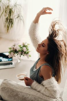 a relaxed girl at home drinks coffee and watches a movie.Domestic calm.The girl is sitting comfortably on the sofa and drinking coffee.