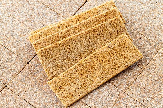 thin crispy loaves of rye flour folded in the form of a background and along them lie chaotically other similar loaves, dietary nutritious food