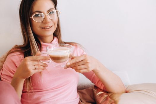 relaxed girl in the morning in pajamas at home drinking coffee .Inner peace.The girl is sitting comfortably on the sofa and drinking coffee dreaming about something.