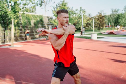 sports man in a red t-shirt on the sports ground doing exercises. High quality photo