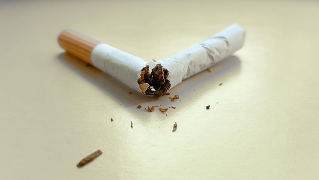 Broken cigarette isolated on a yellow background. View from above.