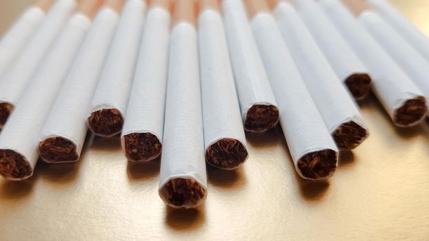 Image of several commercial cigarettes. pile of cigarettes on a gold background or concept of anti-smoking campaign, tobacco.