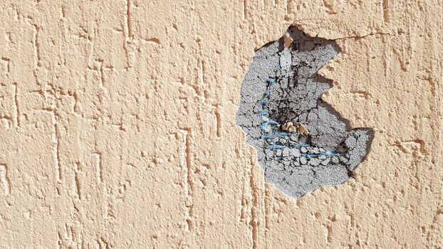 dent on a yellow concrete wall. Hole in the wall with foam insulation. Crack on the yellow wall with decorative putty.
