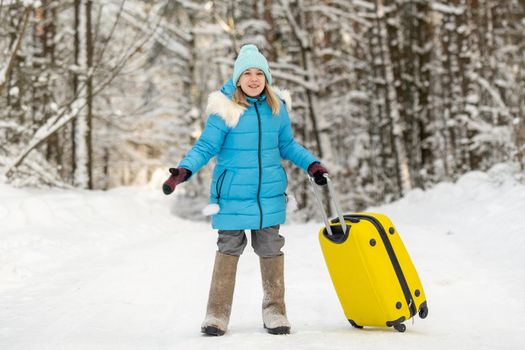 A girl in winter in felt boots goes with a suitcase on a frosty snowy day.