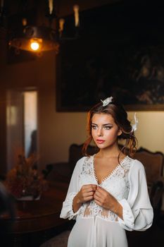 a bride in underwear and a white robe in the interior of a Villa in Italy at a wedding.morning of the bride in Tuscany.boudoir photo session at the Villa