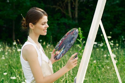 cheerful woman paints a picture palette nature landscape. High quality photo