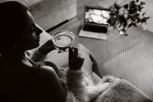 a relaxed girl at home drinks coffee and watches a movie.Domestic calm.The girl is sitting comfortably on the sofa and drinking coffee.