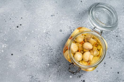 Pickled mushrooms champignons in a glass jar. Gray background. Top view. Copy space.