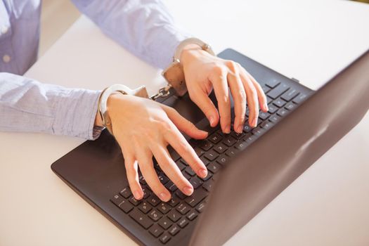 Woman hands locked to laptop by chain on keyboard of notebook.