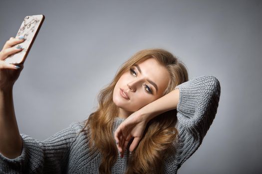 Portrait of a cheerful girl looking at mobile phone isolated over gray background