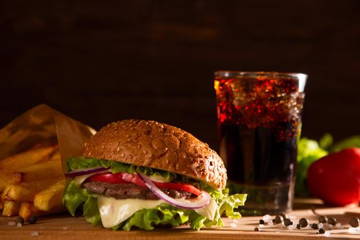 american snack with big burger and glass cola on wooden table.