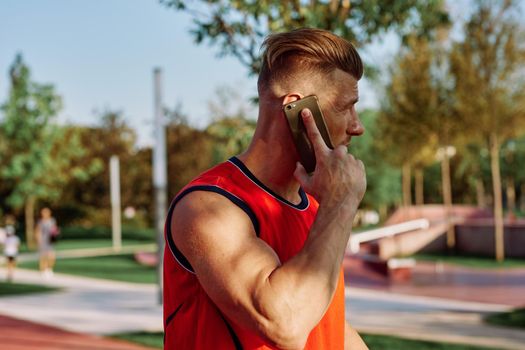 athletic man talking on the phone in the park. High quality photo