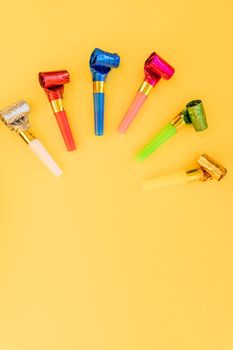 Birthday party whistles on color background