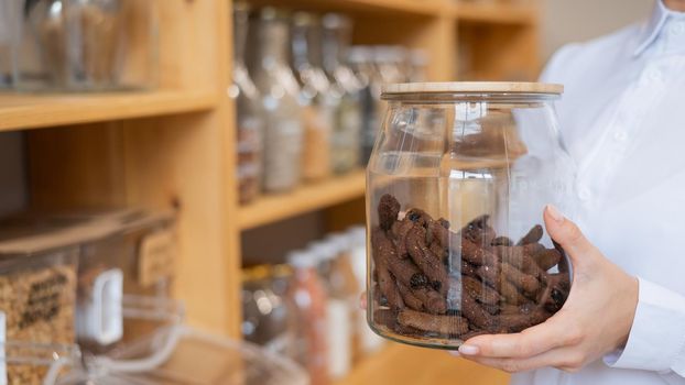 A woman holds croutons in a glass jar. Eco shop without plastic waste