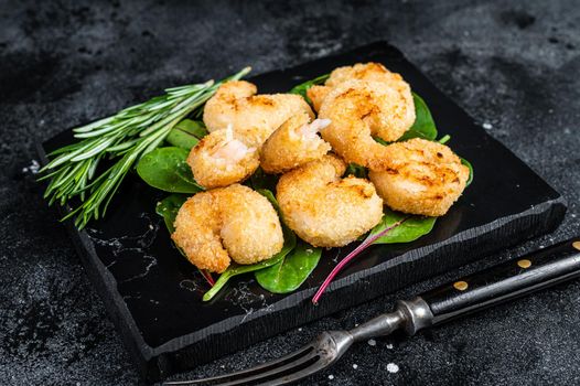 Roasted Crispy Shrimps Prawns on a marble board with green salad. Black background. Top view.