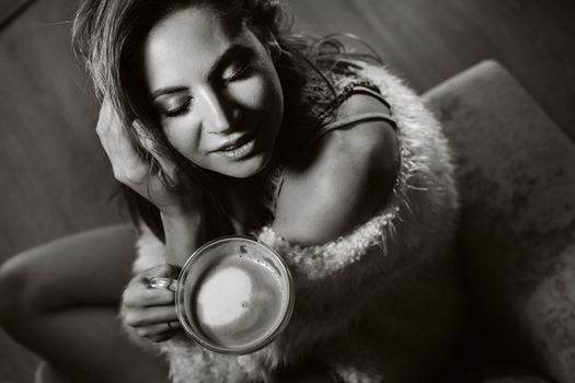 relaxed girl at home drinking coffee.Inner peace.The girl is sitting comfortably on the sofa and drinking coffee.black and white photo