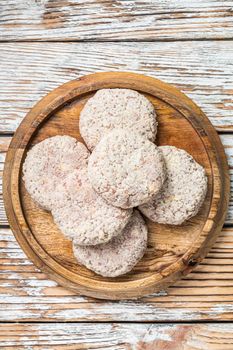 Raw chicken patty cutlet with breadcrumbs. White wooden background. Top view.