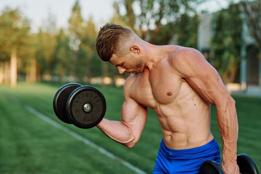 sporty man with pumped up body in park workout exercise. High quality photo