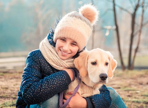 Portrait of beautiful girl hugging dog outdoors