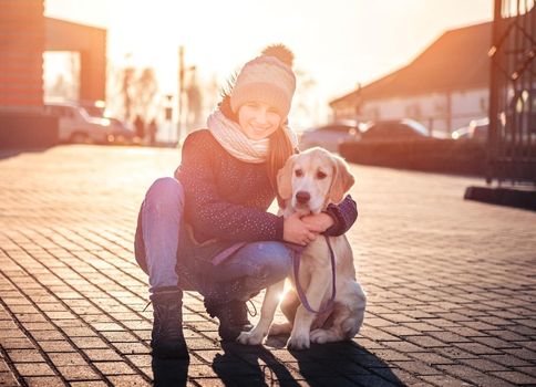 Cute girl hugging beautiful dog in street