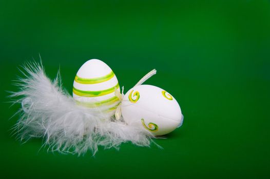 easter egg in white feathers nest over green background