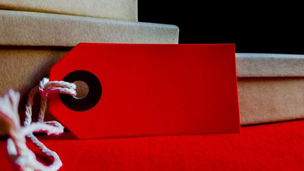 Cardboard boxes with a tag. Brown packing box with blank label and copy space on red backdrop.