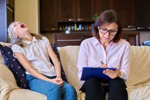 Smiling positive child girl and female psychologist teacher at session. Preteen student talking to counselor mentor therapist sitting on couch. Children mental health psychology childhood adolescence
