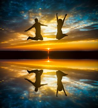 silhouette of couple jumping in sunset